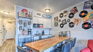 Eine Küche mit Barbereich, weißen Schränken und einer Wand, die mit Schallplatten dekoriert ist.