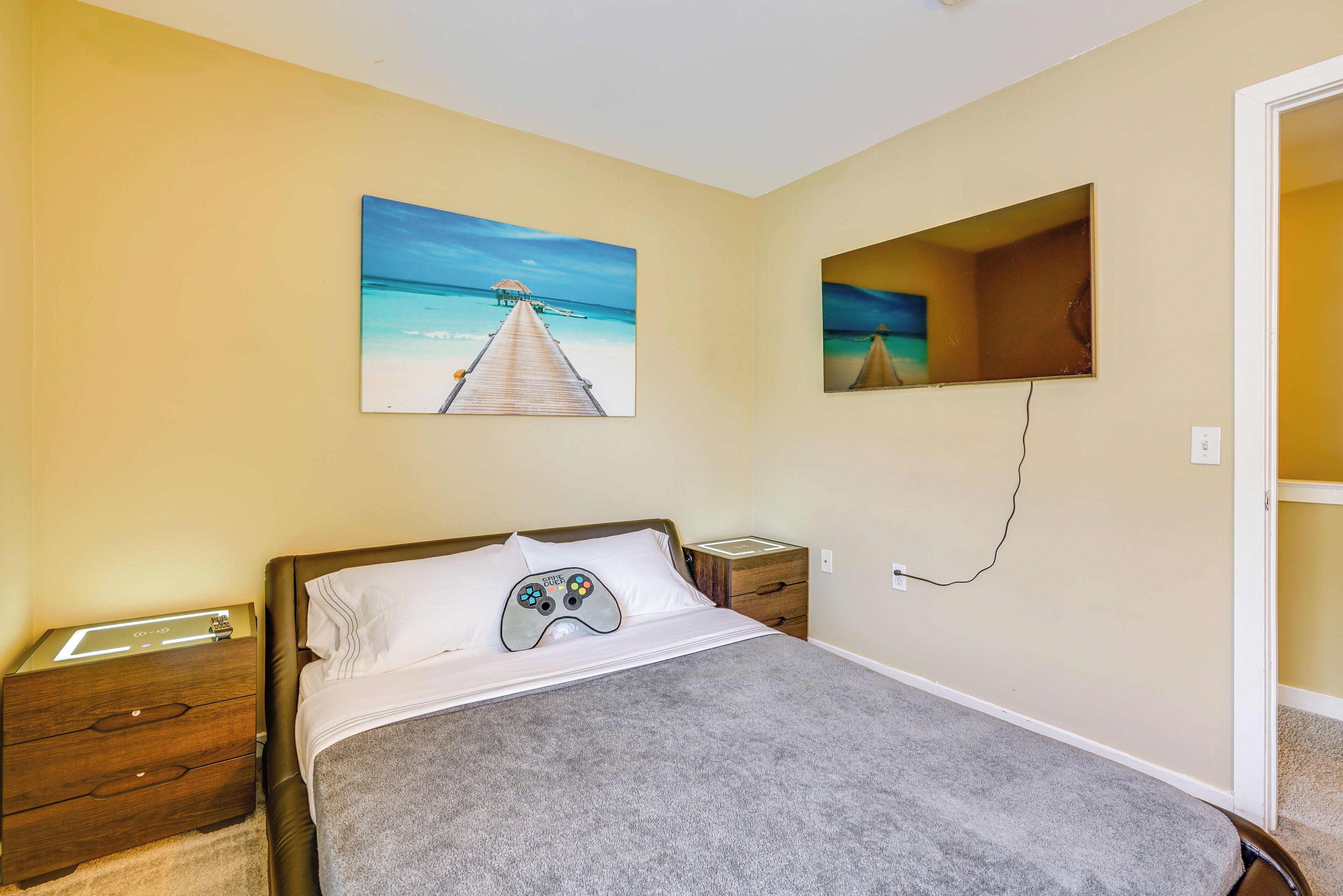 A bedroom with a bed, a nightstand, a bedside table, and a wall-mounted TV.