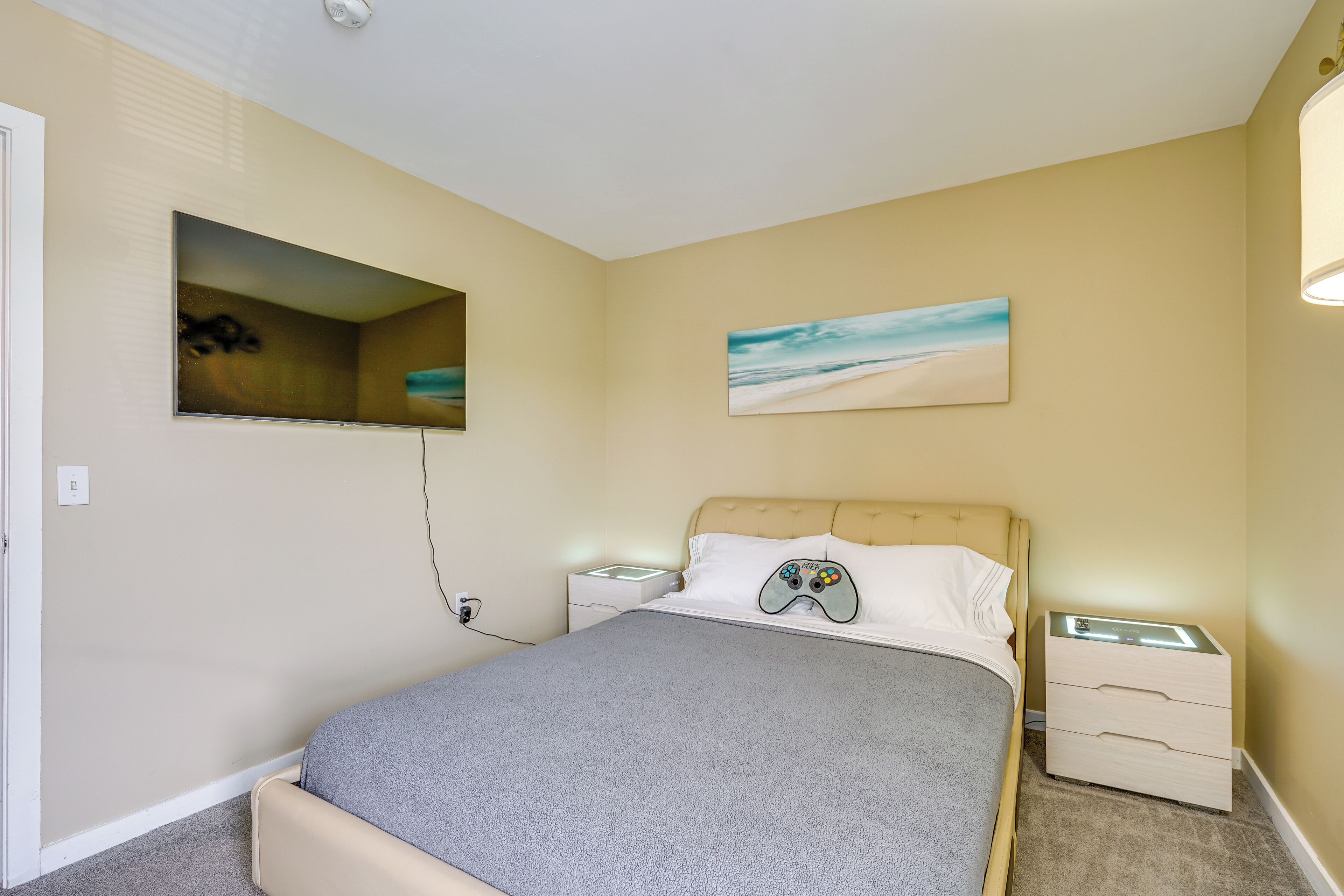 Ein Schlafzimmer mit Bett, Nachttischen, einem Wandregal und Kunstwerken.