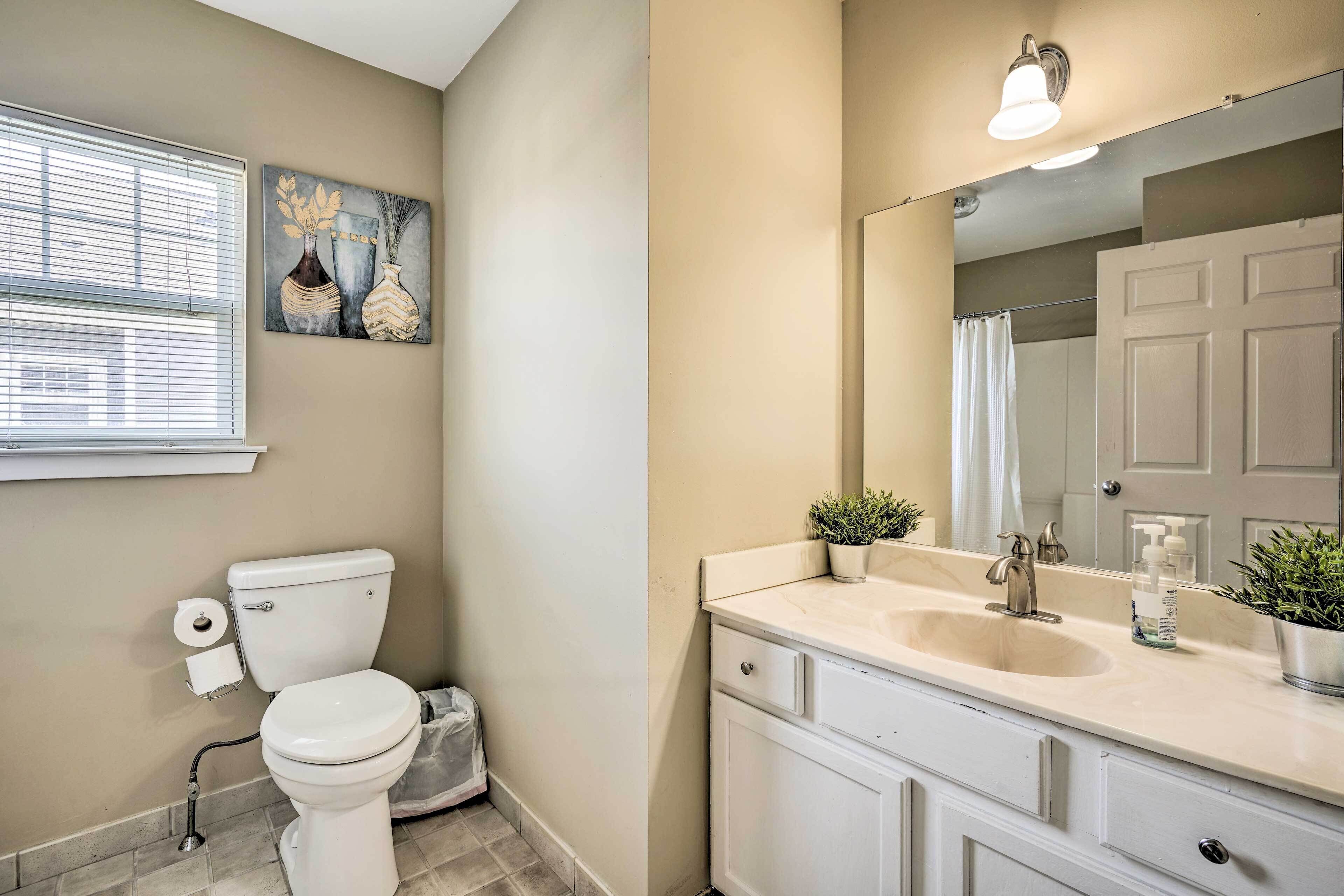 A bathroom with a toilet, sink, and mirror.