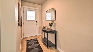 A hallway with a white door, a small table with a vase and a bowl, and a black rug. - Belgrade Vacation Rental w/ Mountain Views! (Belgrade)