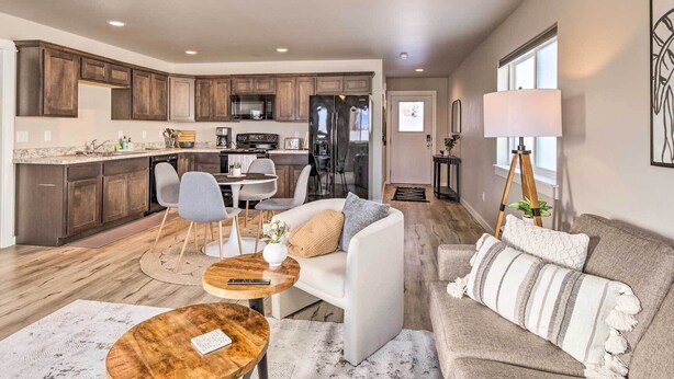 A modern living room with a sofa, coffee table, and chairs, a kitchen with wooden cabinets and appliances, and a dining area with a table and chairs. - Belgrade Vacation Rental w/ Mountain Views! (Belgrade)