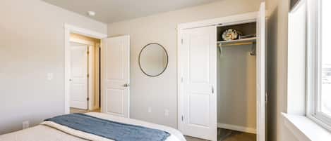 A bedroom with a bed, a closet, and a window.