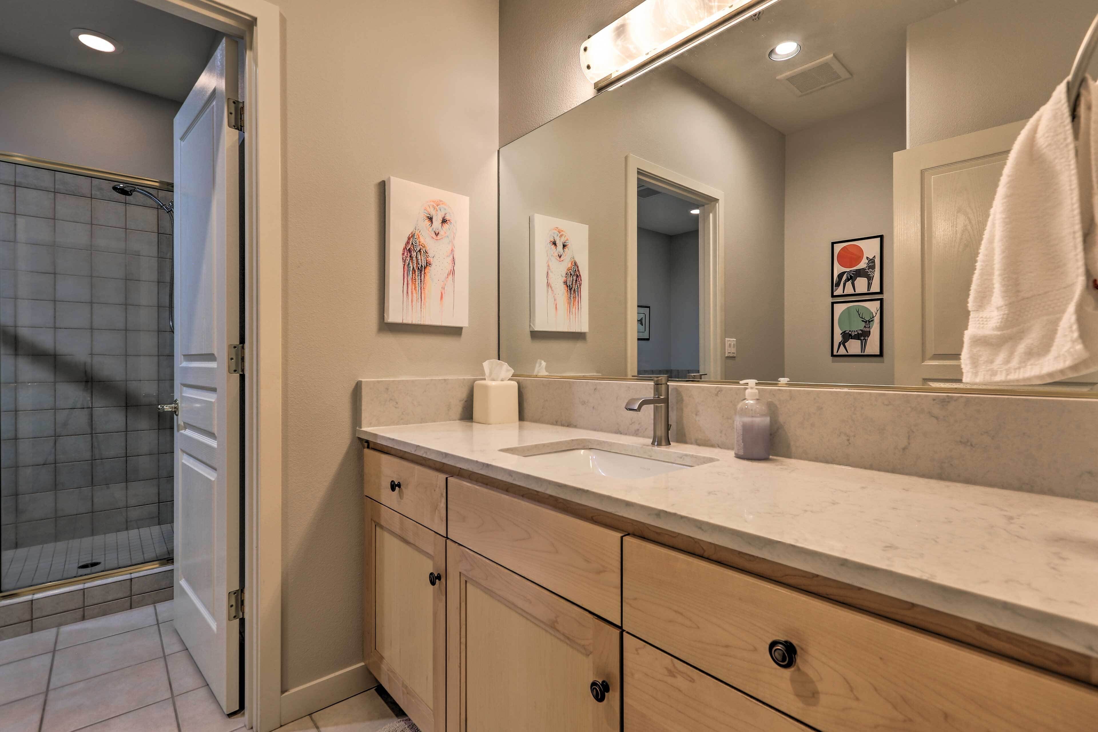 A bathroom with a large mirror, a sink, a towel rack, and a shower area.
