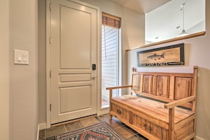 A wooden bench with a rustic design, a white door with a silver handle, and a wall-mounted fish sign indicating a nearby location. - Bend Townhome w/ Golf Course Views & Private Deck! (Bend)