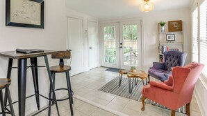 A spacious room with a dining area, a seating area with a chair, a bookshelf, and a door leading outside. - Adorable Baton Rouge Cottage < 3 Mi to Lsu! (Baton Rouge)