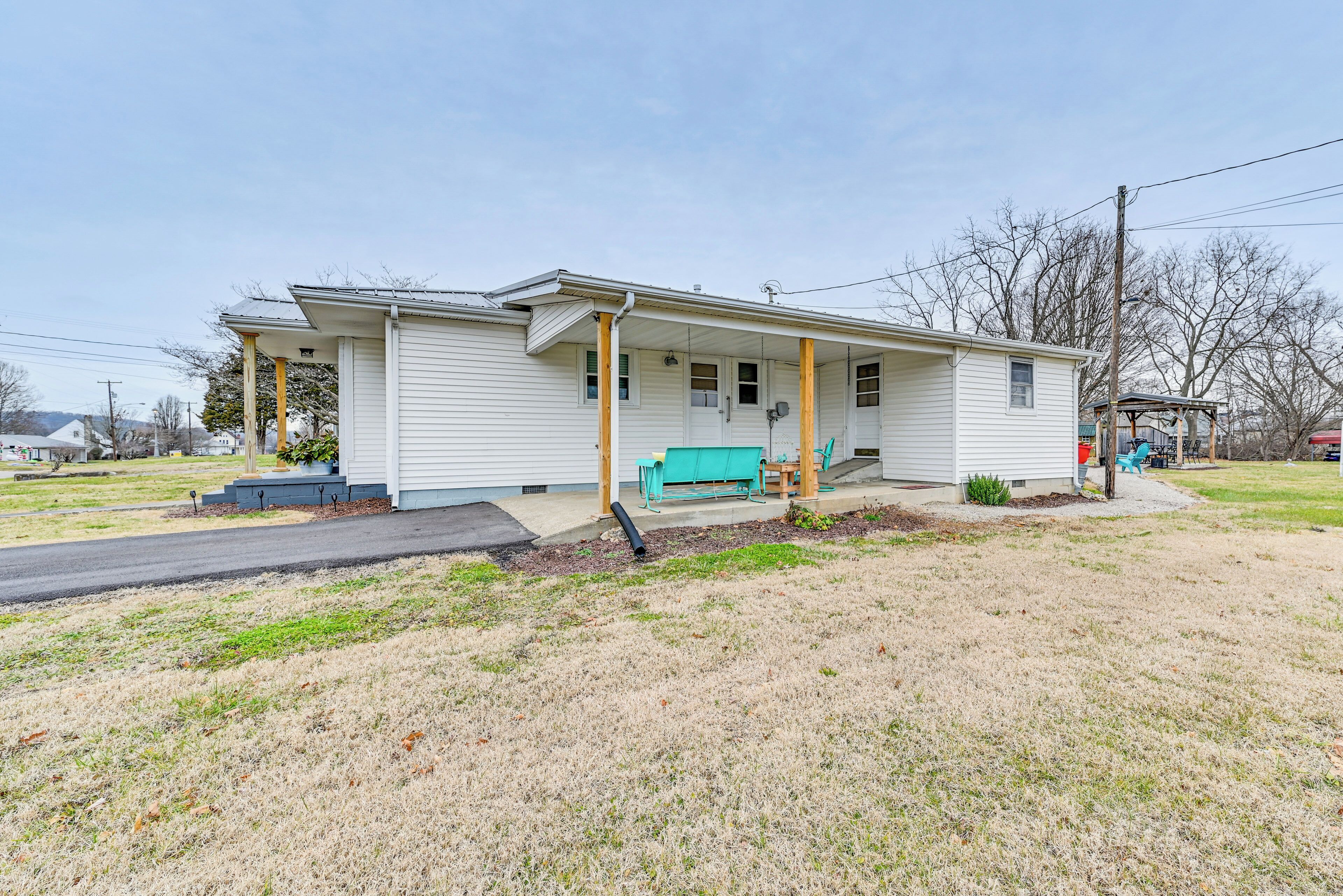 A single-story house with a porch, a green bench, and a small outdoor seating area.