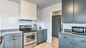 A kitchen with grey cabinets, a stainless steel oven, a microwave, and a tiled backsplash.