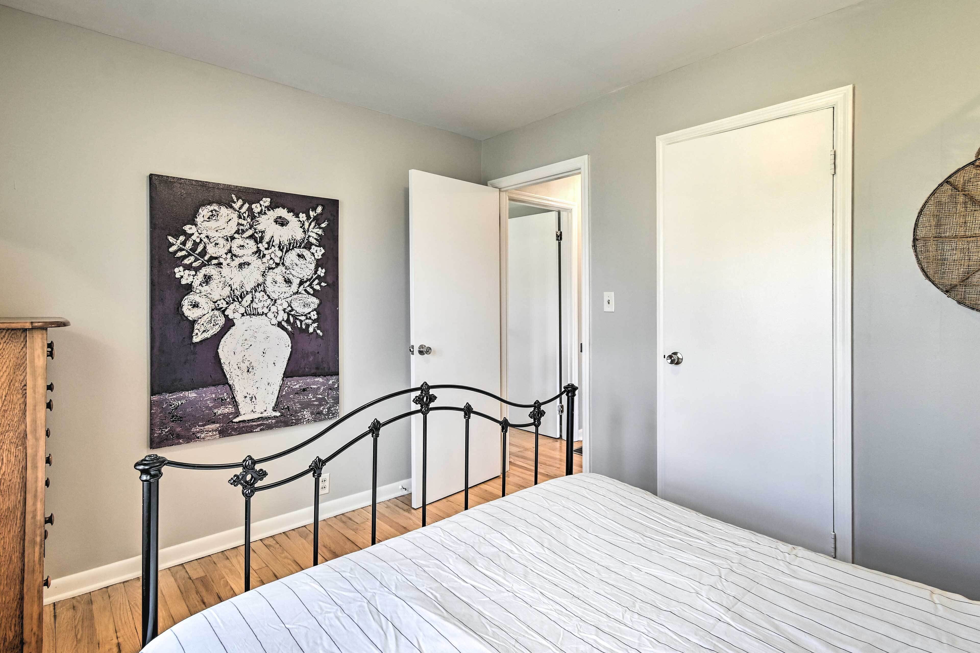 A bedroom with a bed, a door, and a wall-mounted fan.