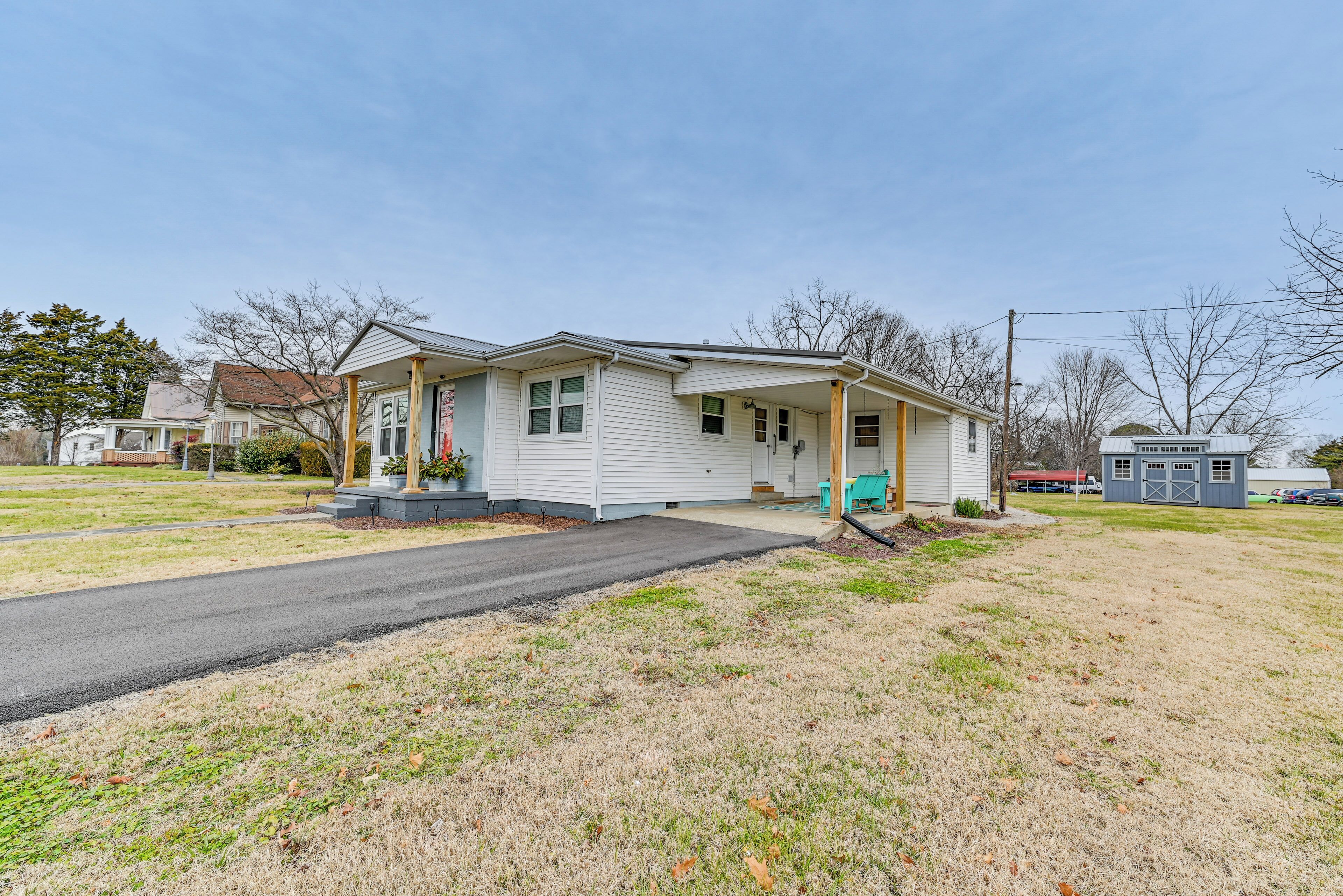 A single-story house with a front porch, a garage, and a small shed in the background.