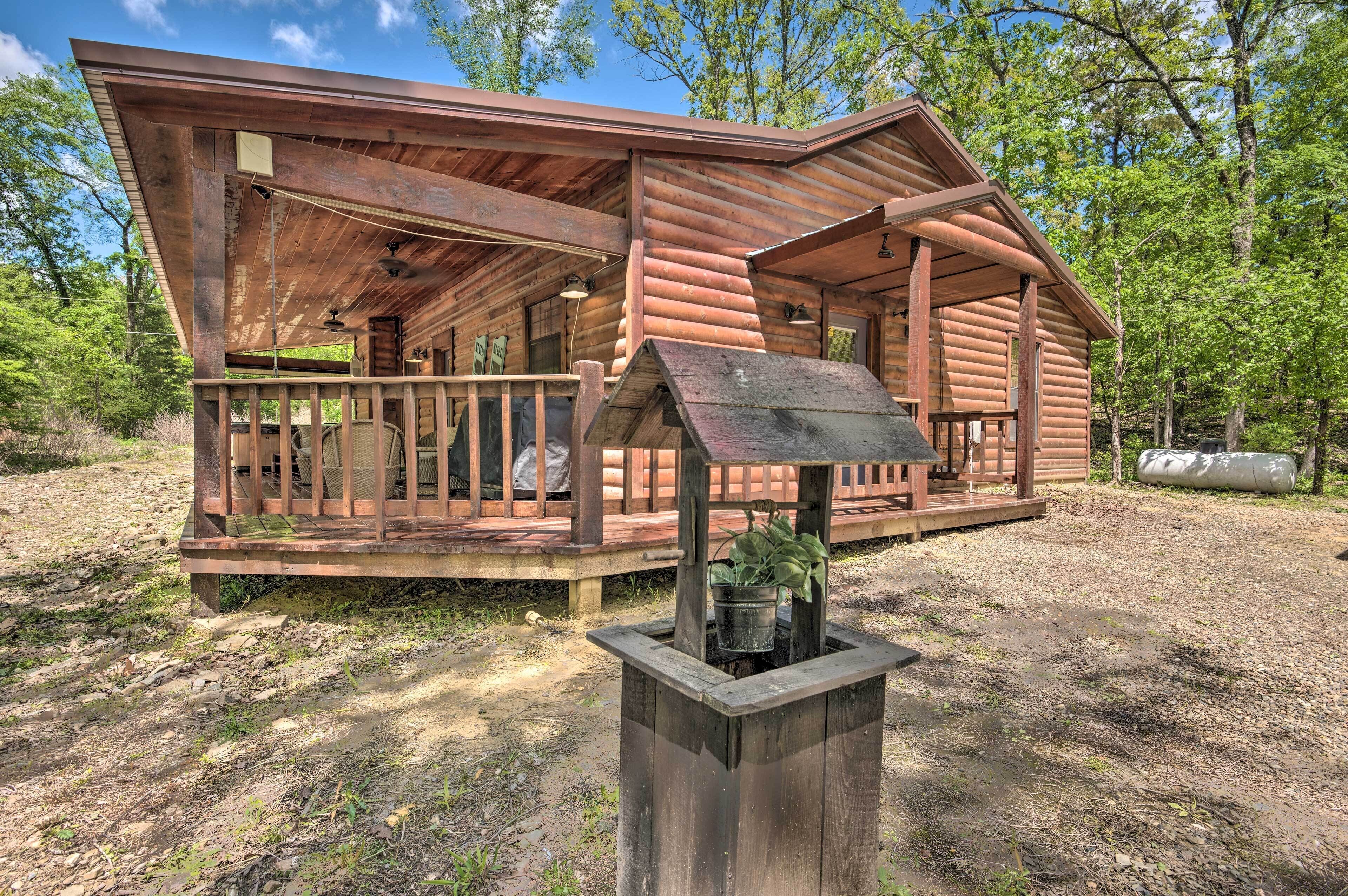 A rustic log cabin with a porch, a small deck, and a wooden planter in front.