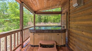 A wooden deck with a hot tub, a wooden bench, and a view of the surrounding forest. - Cabin w/ Hot Tub - Near Broken Bow Lake & Hiking! (Broken Bow)