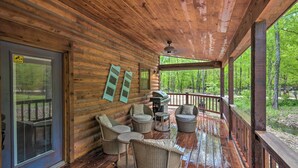 A wooden deck with wicker furniture and a grill, overlooking a forested area. - Cabin w/ Hot Tub - Near Broken Bow Lake & Hiking! (Broken Bow)