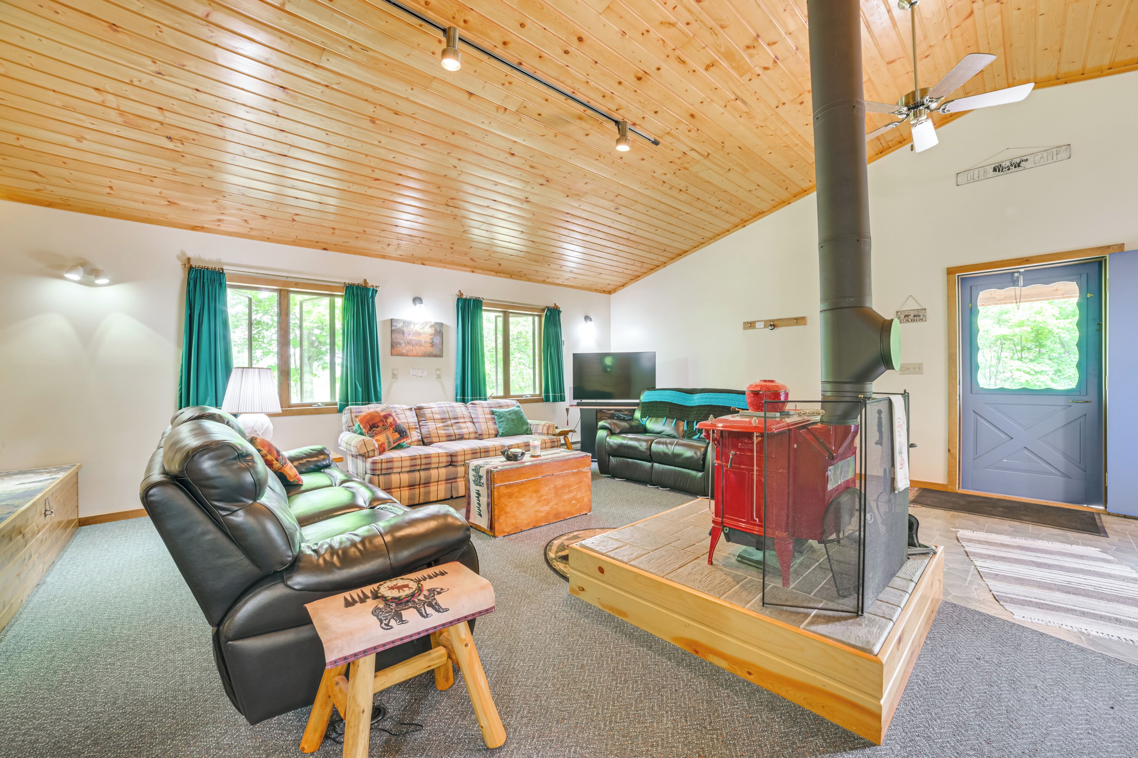 A cozy cabin interior with a fireplace, leather sofa, and a flat-screen TV.