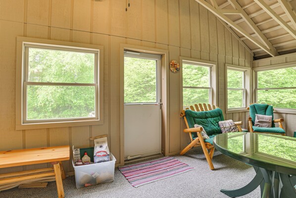 A cozy room with large windows, wooden furniture, and a picnic table. - Michigan Retreat on 10 Acres: Hike, Fish & Explore (Moran)