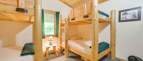 A bunk bed room with a small table and a fan.
