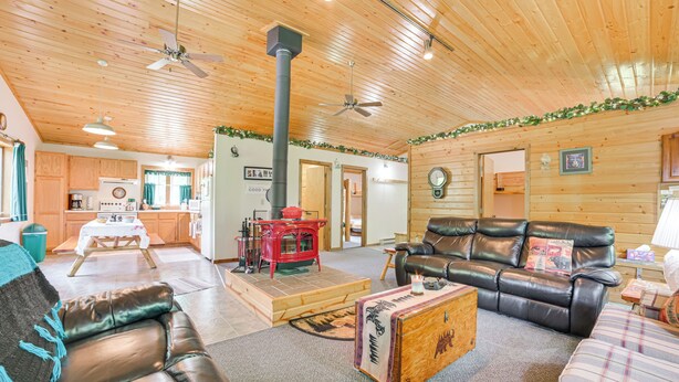 A cozy cabin interior with a fireplace, leather furniture, and a kitchen area.