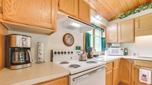 A kitchen with wooden cabinets, a white stove, a coffee maker, and a microwave.