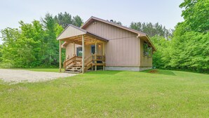 A two-story wooden cabin with a covered porch and a staircase leading to the entrance.