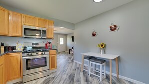A modern kitchen with wooden cabinets, stainless steel appliances, and a white dining area with a vase of sunflowers. - All-season Getaway in Frederic: Bring Your Pets! (Frederic)