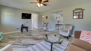 A living room with a ceiling fan, a flat-screen TV, a coffee table, a patterned rug, and a sofa. - All-season Getaway in Frederic: Bring Your Pets! (Frederic)