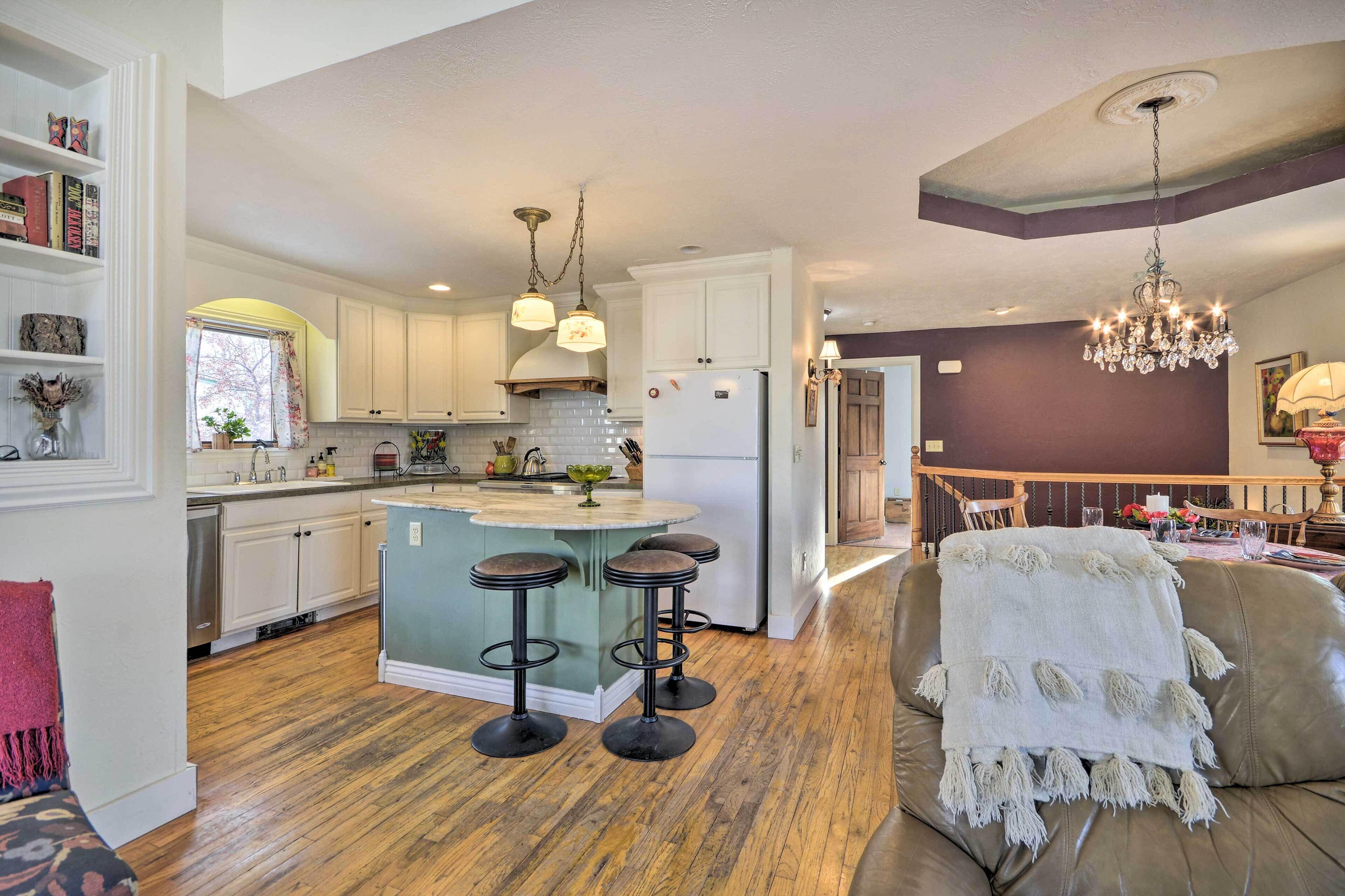 A spacious kitchen with white cabinets, a central island with stools, and a dining area with a chandelier.