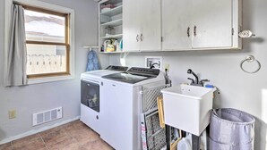 Une buanderie équipée d’un lave-linge et d’un sèche-linge, d’un évier et d’armoires au-dessus.