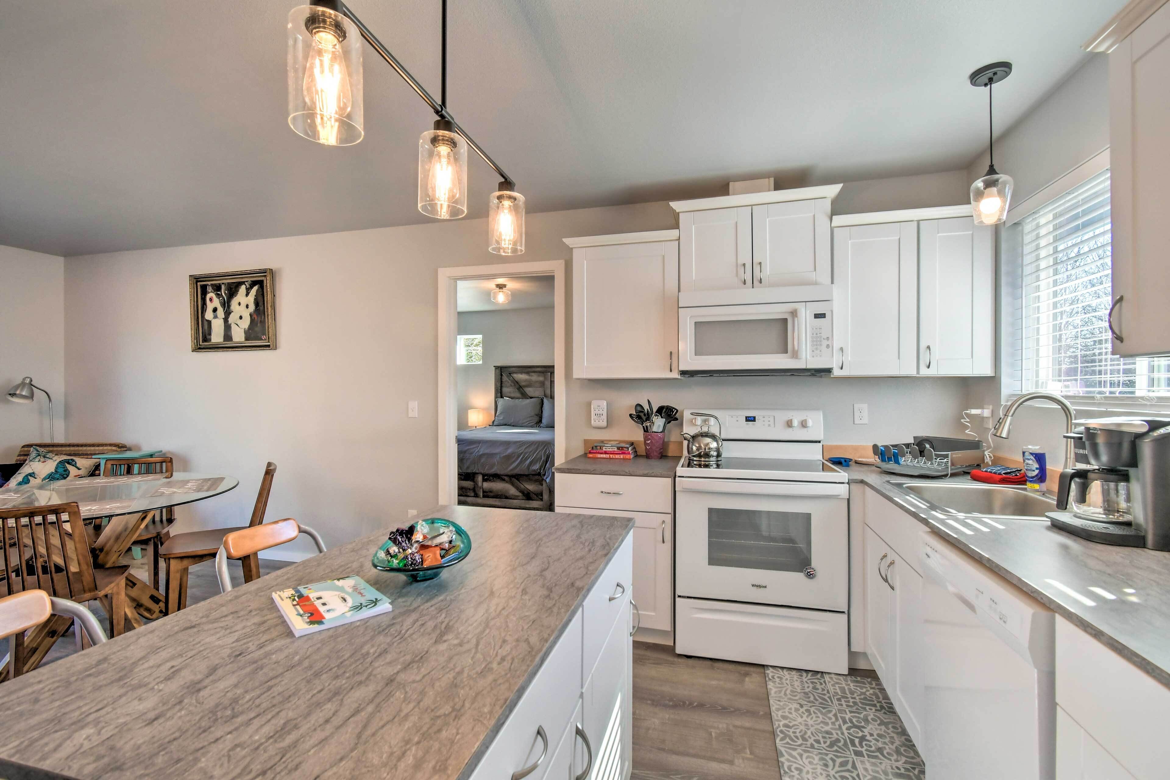 Een moderne keuken met witte kastjes, een inbouwoven en een eethoek met een ronde tafel en stoelen.