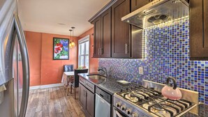 A kitchen with dark wooden cabinets, a stainless steel stove, and a colorful mosaic backsplash. - Charming New York Escape Near Central Park! (Jericho)