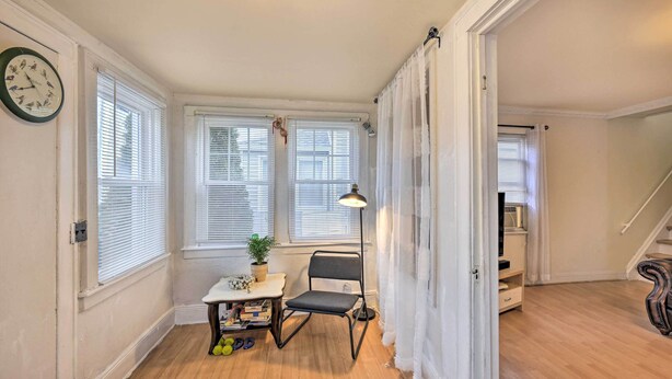 A room with wooden flooring, a desk with a lamp, a chair, and a clock on the wall. - Charming New York Escape Near Central Park! (Jericho)