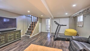 A living room with a treadmill, a television, and a staircase. - Charming New York Escape Near Central Park! (Jericho)