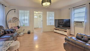 A living room with a sofa, a TV, a hanging chair, and a chandelier. - Charming New York Escape Near Central Park! (Jericho)