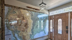 A large wall map in a hallway with wooden flooring and a wooden door with stained glass windows. - Charming Texas Home w/ Stunning Canyon Views! (Canyon)