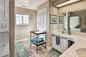 A bathroom with a white sink, a mirror, a window, and a towel rack.