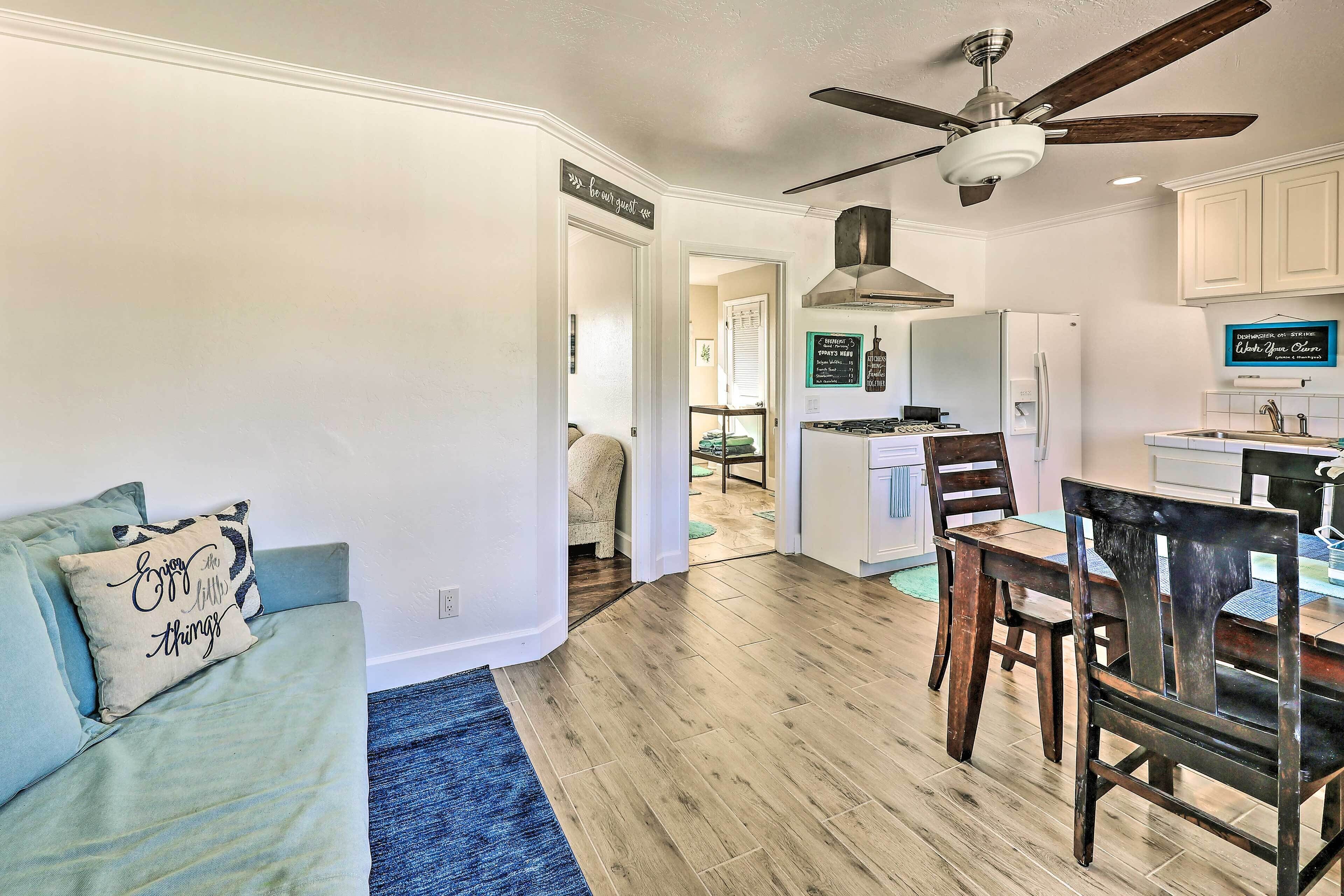A modern kitchen with white cabinets, a built-in oven, and a dining area with wooden chairs and a table.