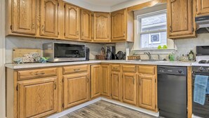A kitchen with wooden cabinets, a microwave, a dishwasher, and a window with a view of the outside. - Charming Hamden Home: 2 Mi to Yale University (Hamden)