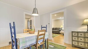A dining area with a table set for two, a chandelier, and a view into the living room. - Charming Hamden Home: 2 Mi to Yale University (Hamden)