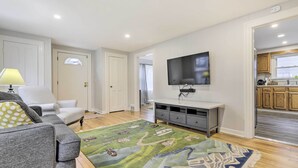 A living room with a grey sofa, a television, a patterned rug, and wooden flooring. - Charming Hamden Home: 2 Mi to Yale University (Hamden)