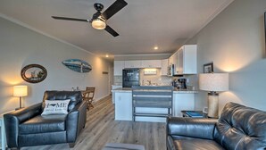 A modern living room with leather sofas, a dining area, and a kitchen with white cabinets.