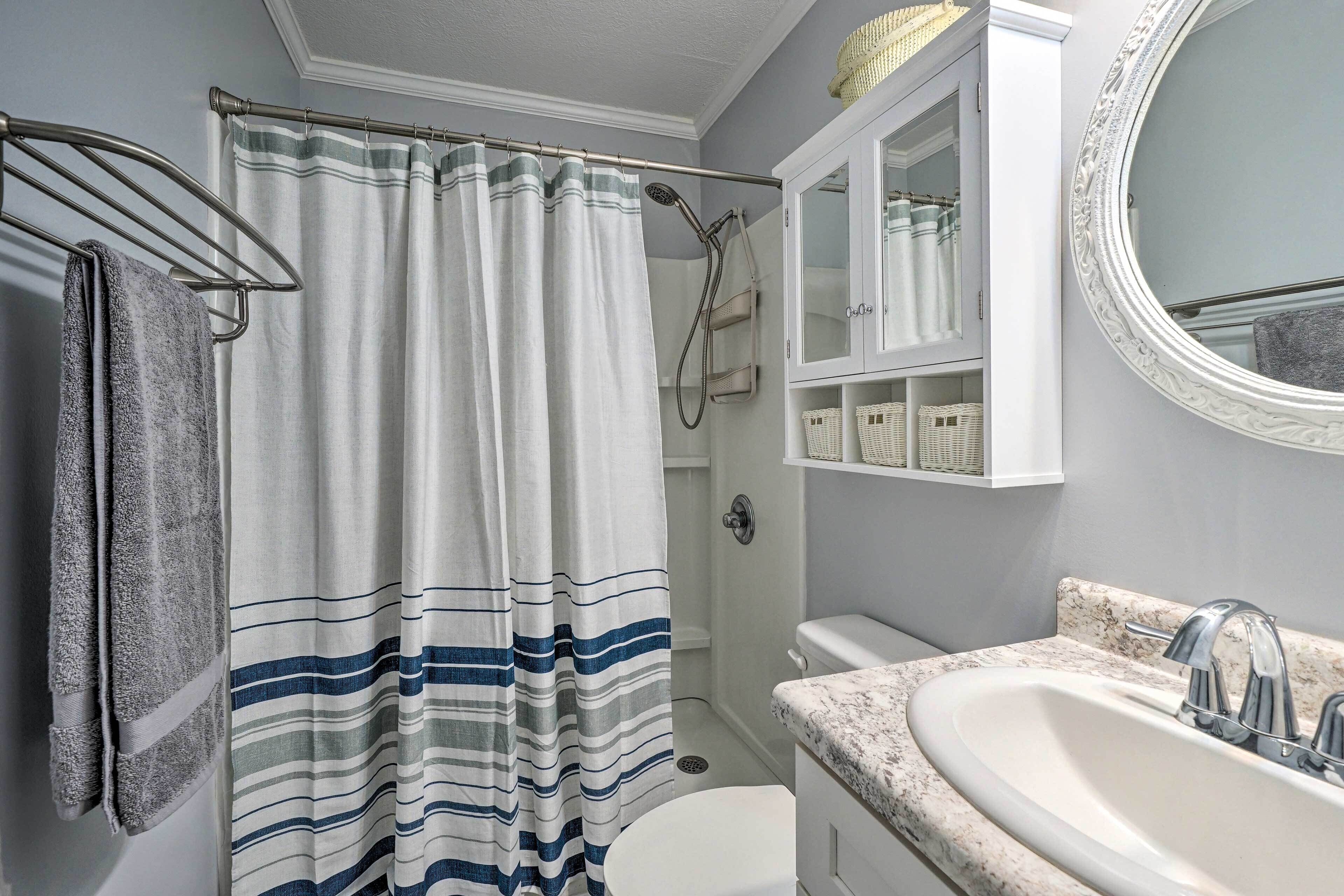 A bathroom with a shower curtain, a toilet, a sink, and a mirror.