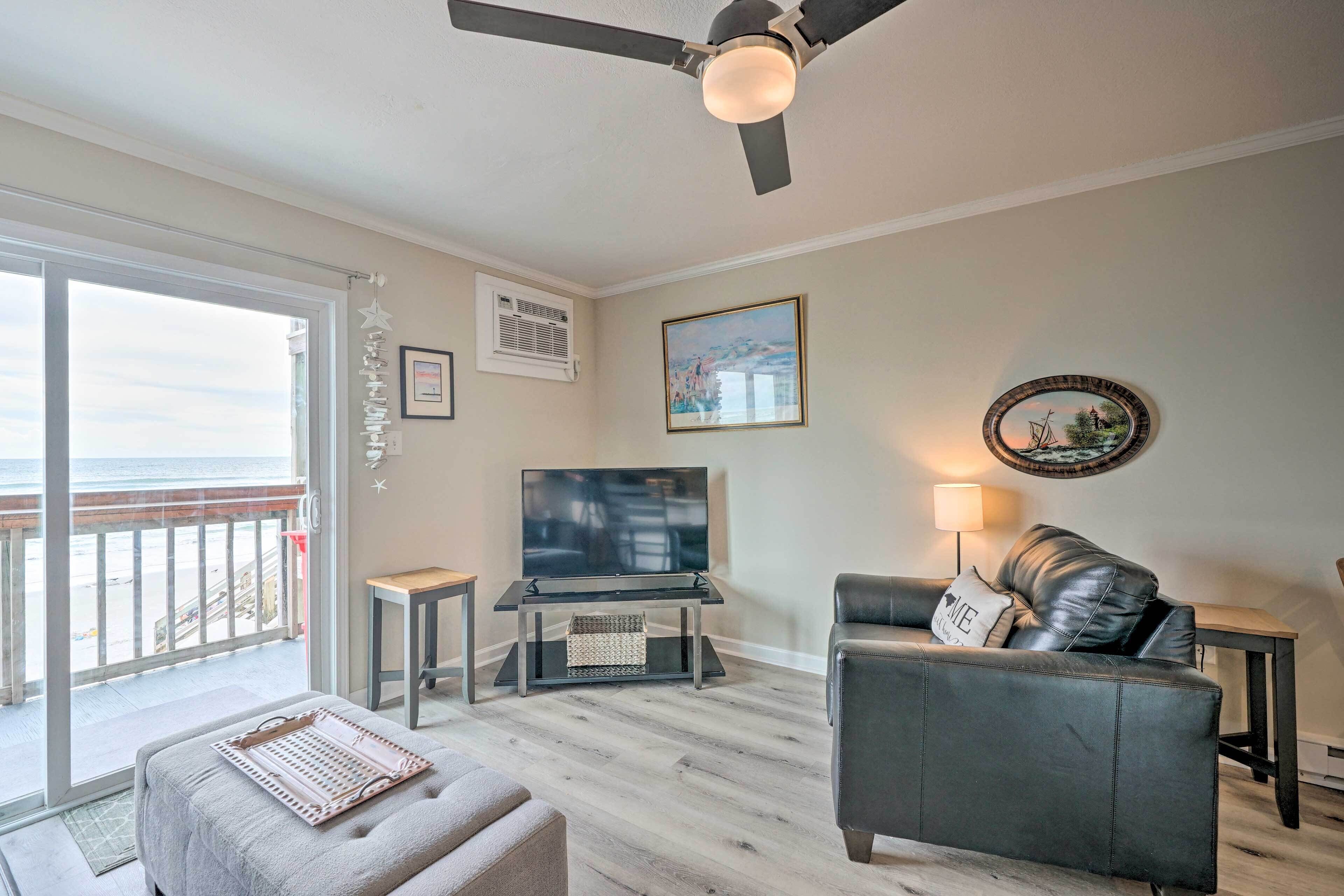 A living room with a TV, a sofa, a coffee table, and a balcony with a view.