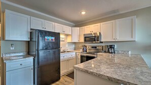 A modern kitchen with white cabinets, a stainless steel refrigerator, a microwave, and a coffee maker.