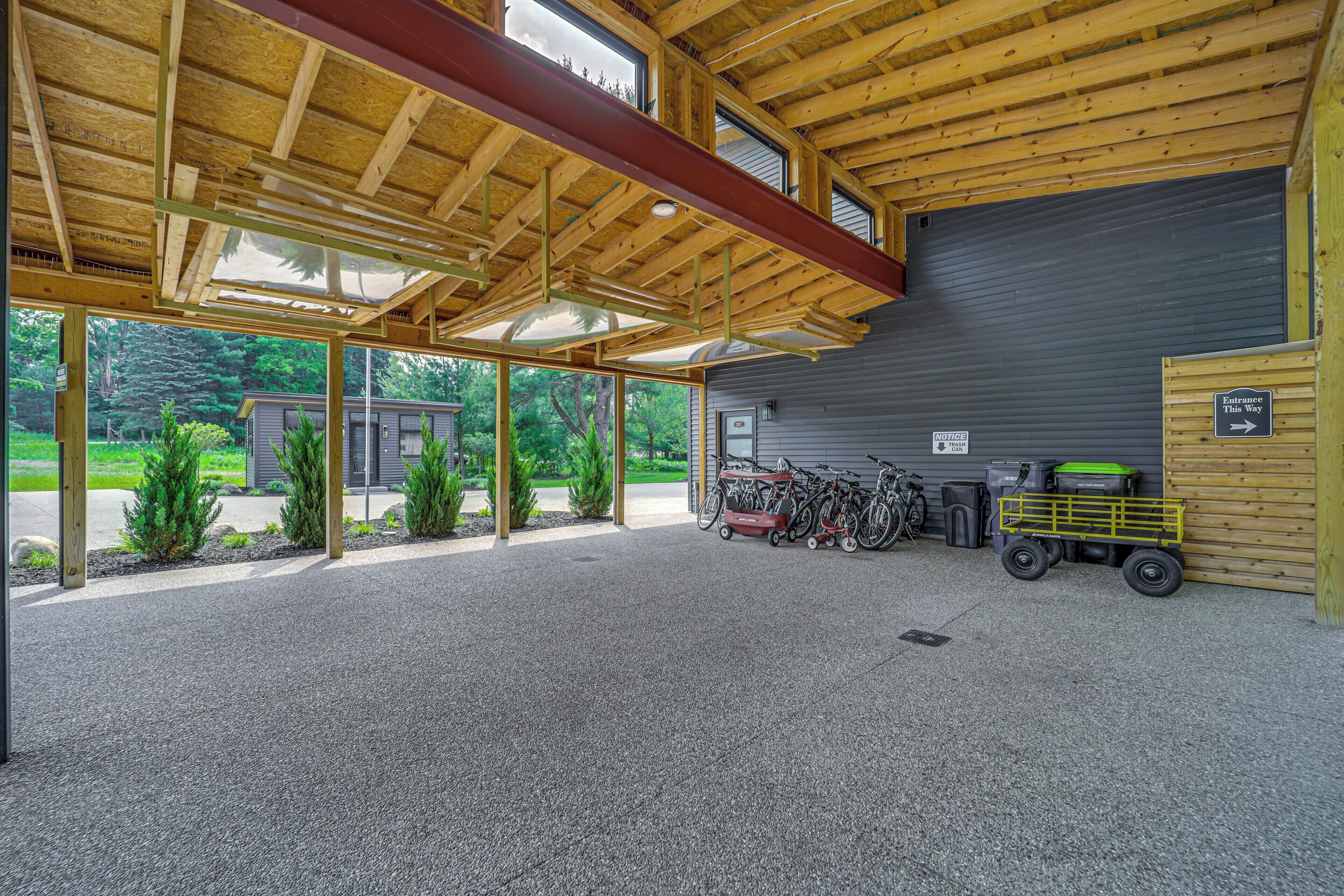 A covered outdoor area with a gravel floor, wooden beams, and a large garage door.