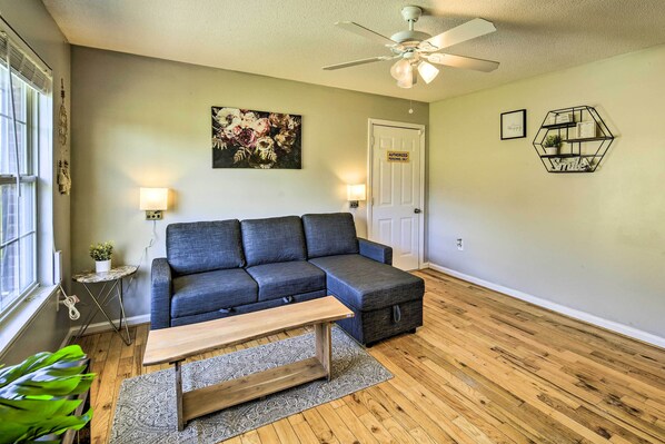 A living room with a sectional sofa, a wooden coffee table, a patterned rug, a ceiling fan, and a door with an 'Authorized Personnel Only' sign.