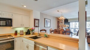 Una cocina moderna con armarios blancos, electrodomésticos de acero inoxidable y encimera de madera.