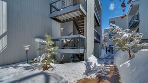 Un sendero cubierto de nieve entre edificios, con una escalera que sube a un nivel superior.