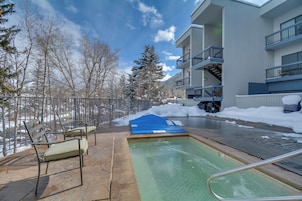 Área de piscina com tapete azul, cadeiras de metal e cerca metálica.