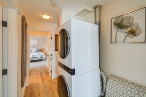 A laundry area with a washing machine and dryer, a hallway leading to a bedroom, and a framed artwork on the wall. - Private Ski Retreat in Avon: Eagle River Views! (Avon)