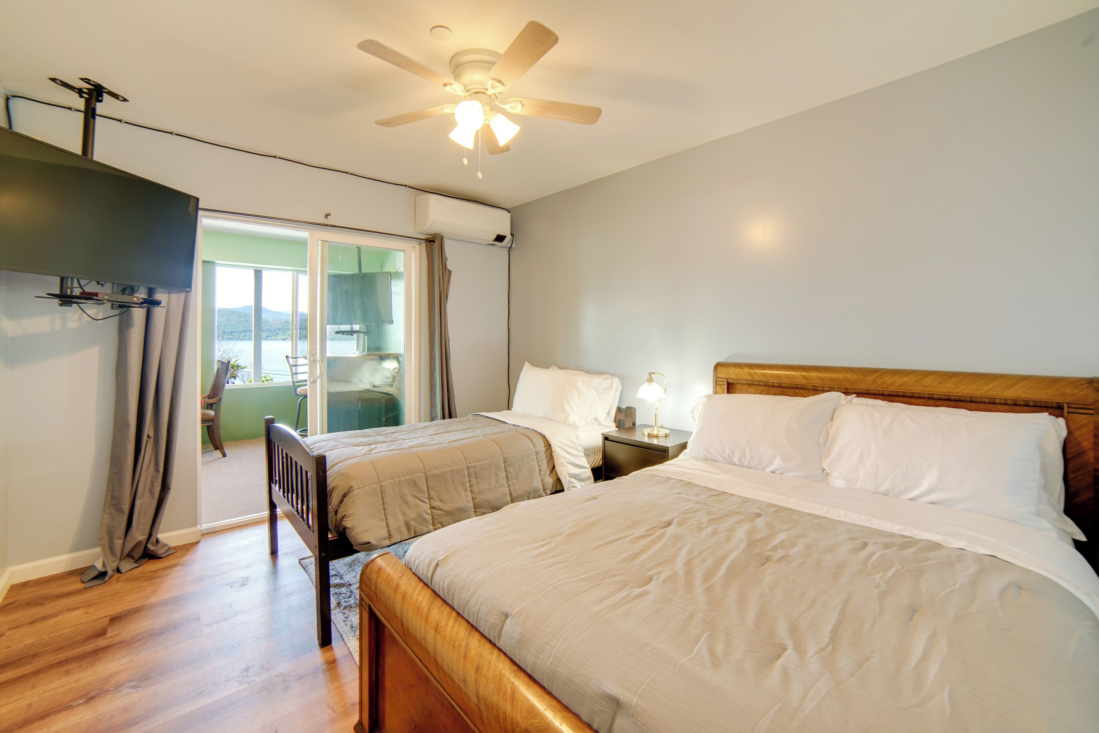 A bedroom with two beds, a ceiling fan, and a view of the outdoors.
