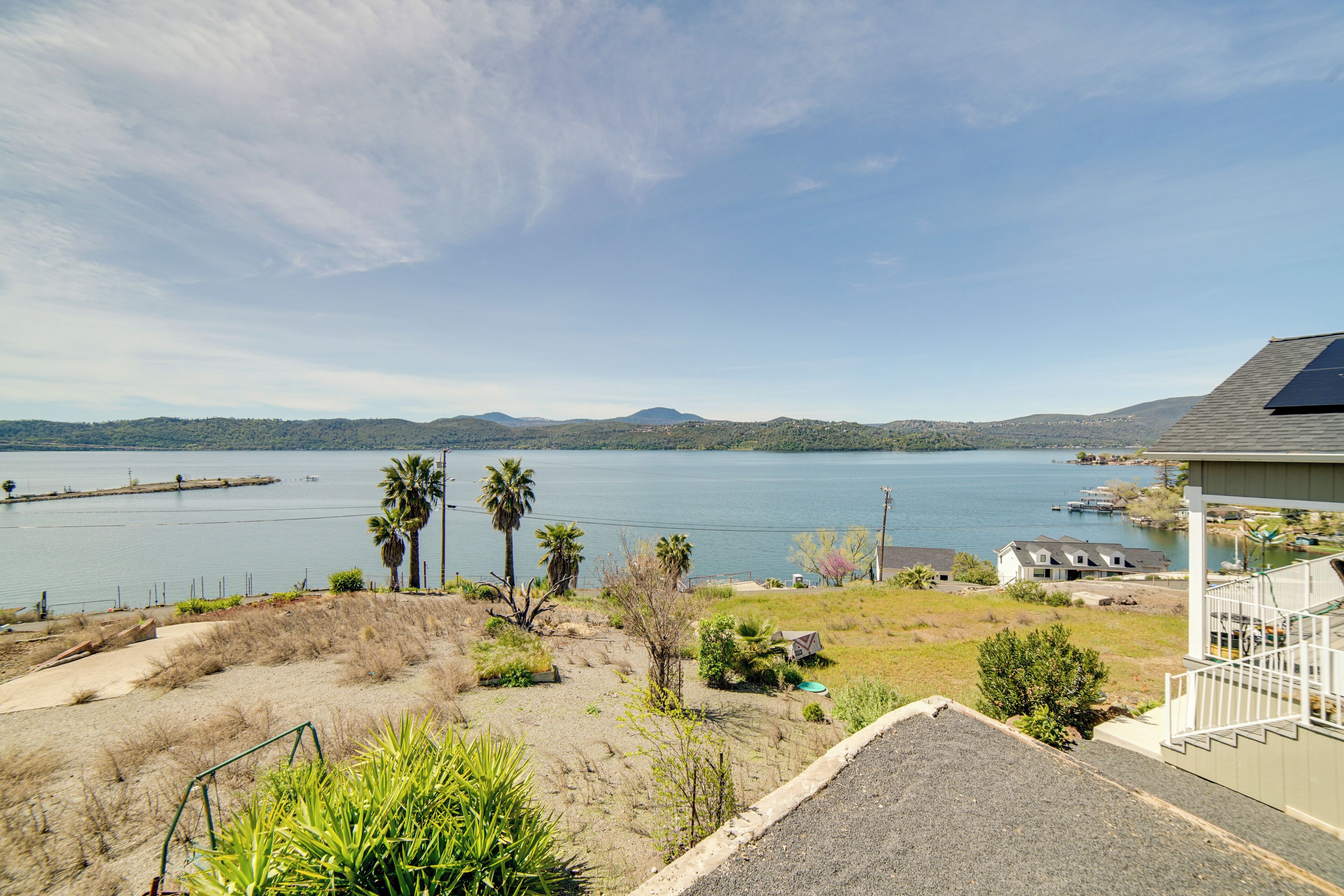 A coastal property with a view of the sea, a sandy area with sparse vegetation, and a house with a solar panel.